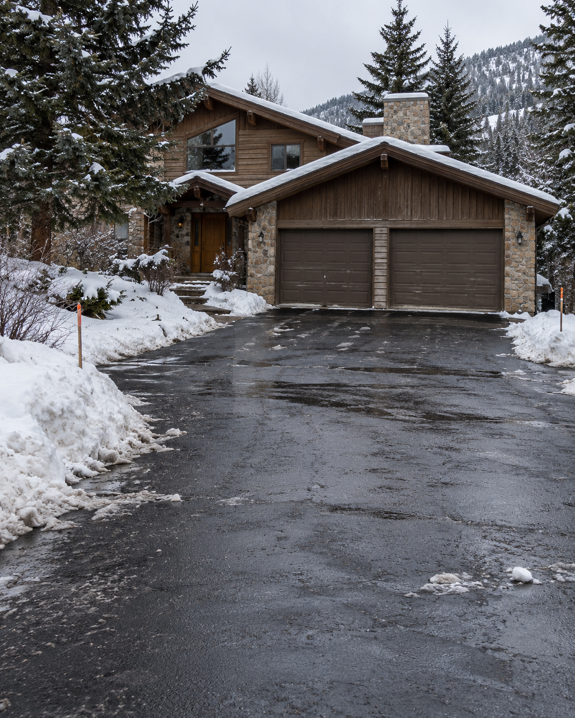 Cleared asphalt driveway outside a timber and stone mountain home